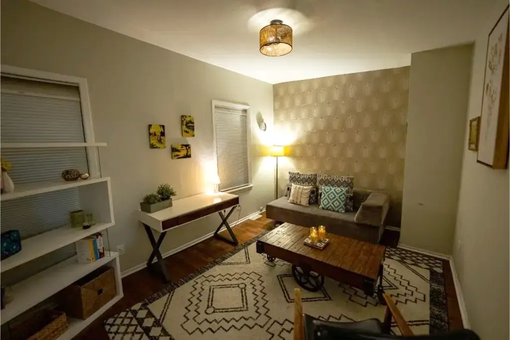 Modern therapy room with a gray couch, wooden coffee table, and patterned rug.